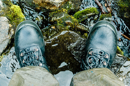 徒步旅行者自然河边的黑山靴子为旅游者穿脚鞋徒步登山提供防水靴子户外图片