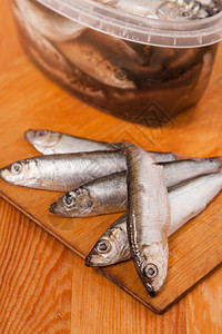 渔业小吃以木制背景盒装的盐咸凤尾鱼渍的图片