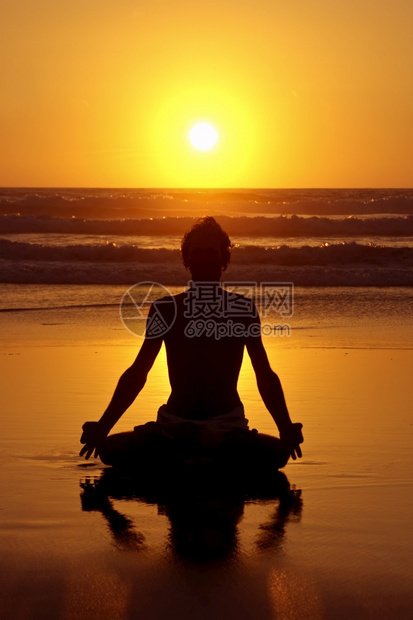 早晨日落时沙滩上冥想的人图片