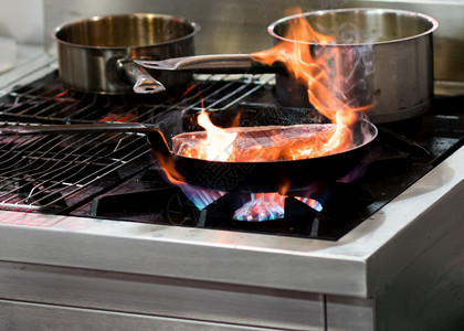手食谱厨师在房炉灶的煎锅中用火焰做饭汤图片