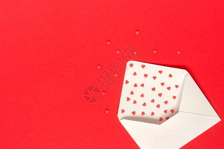 白色的浪漫约会红糖果洒心飞出白纸信封位于红色背景的左侧顶视图复制文本概念情人节和卡片礼物带有爱的消息红色糖果洒心飞出红色背景的白图片