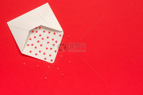 红糖从白纸信封上撒洒糖果心放在红色背景的左边最白纸信封上复制文本空间情人节和卡礼物以爱来传递的信息红甜会喷洒糖果心在红色背景的白图片
