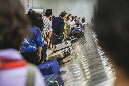 飞手推车站许多乘客在国际机场等待行李箱或携带流动传送的行李这些旅客在机场等候旅行图片