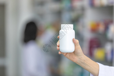 药品货架胶囊药物白色的店剂师手头用白瓶装药背景