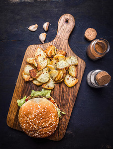 木板可口小吃在切菜板上美味的汉堡土豆加咸盐胡椒和大蒜木制生锈背景图片