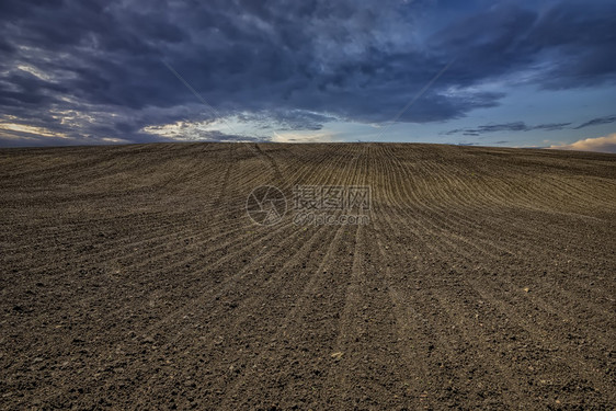 犁过农场沃美丽的犁田和阴云天空场景图片