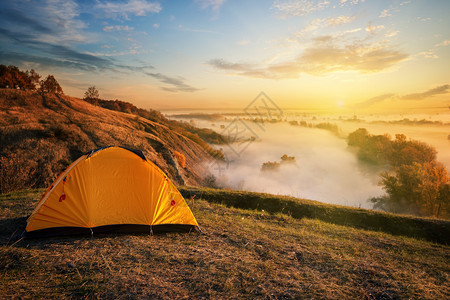 橙子黄昏时在峡谷的橙色帐篷中在浓雾河流上度过寒水日落时在峡谷上的橘色帐篷里旅行自由和隐私的概念美国假期图片