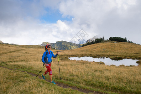 背包孤独棍子单身女孩在山上用徒步木棍走着北欧散步图片