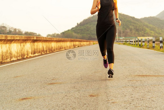 日落女运动员在一条健康道路上奔跑的妇女运动小路行图片