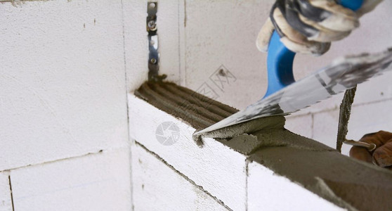 建筑工人在高压土化水泥块墙上平铺迫击床时用粗筋铲平充气工业的职图片