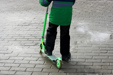 男孩在寒冷的季节骑着滑雪车在公园路边上走着球场新鲜的运动车轮图片