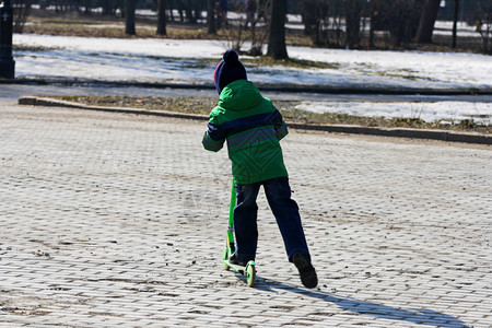 爱好男孩在寒冷的季节骑着滑雪车在公园路边上走着球场户外小型摩托车图片
