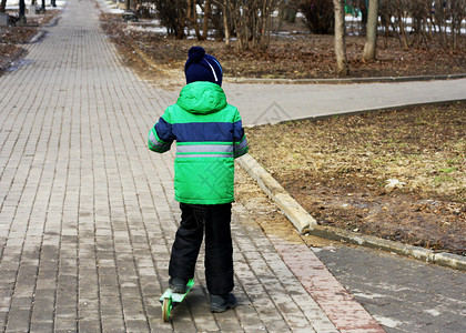 男孩在寒冷的季节骑着滑雪车在公园路边上走着球场乐趣驾驶服装图片