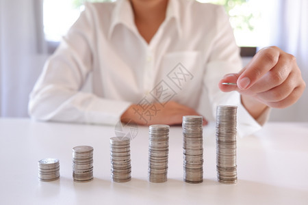 商业界人士将硬币放置在增加的硬币堆叠上成功公司的通货膨胀图片