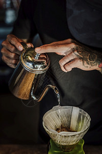 人们筛选手滴咖啡用过滤器在咖啡地面上倒水的Barista咖啡因图片