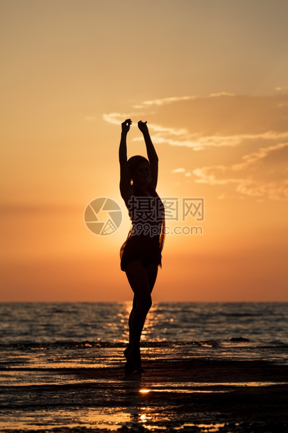 波浪热带快乐的在日落时跳舞一个女孩在海上日落背景跳舞的西尔休埃特舞图片