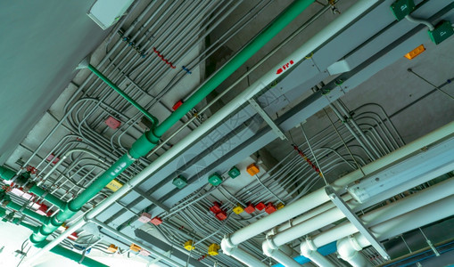 电气安装在聚氯乙烯排水系统塑料管道和工业建筑天花板造上清洁水的电路管道系统和动钢管缆安装在聚氯乙烯上限排水系统塑料管道上工业的红图片