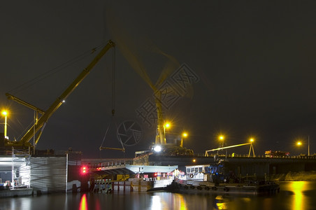 最佳经过道路工程更换运河上的桥梁部分在整个夜晚Twoi起重机即将提升新的部分替换桥由驳船上的拖维持标记Zaandam是一个地名左图片
