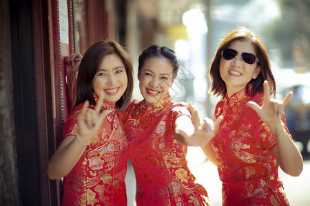 唐人街一群穿着传统服装的亚洲女面带快乐的情绪和手语微笑着容我爱你红色的问候图片