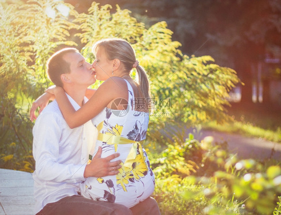 压痛快乐的年轻夫妇在公园户外亲吻浪漫女士图片