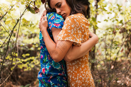追踪年轻的树森林植物包围着两个被拥抱的妇女图片