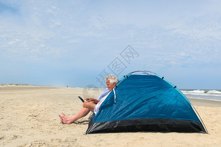 单身老人在海滩的避难所内有数字石板露营药片荷兰互联网图片