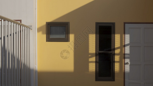 窗户影子白色木制门和储藏室黄屋墙上有阳光和阴影的白色木制门和储存箱灯光栅栏建筑学背景