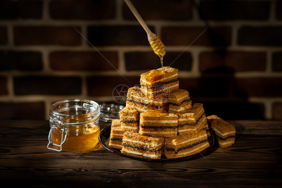 健康焦糖传统的配一片蜂蜜蛋糕和罐子的板块木桌和砖墙背景上加蜂蜜图片