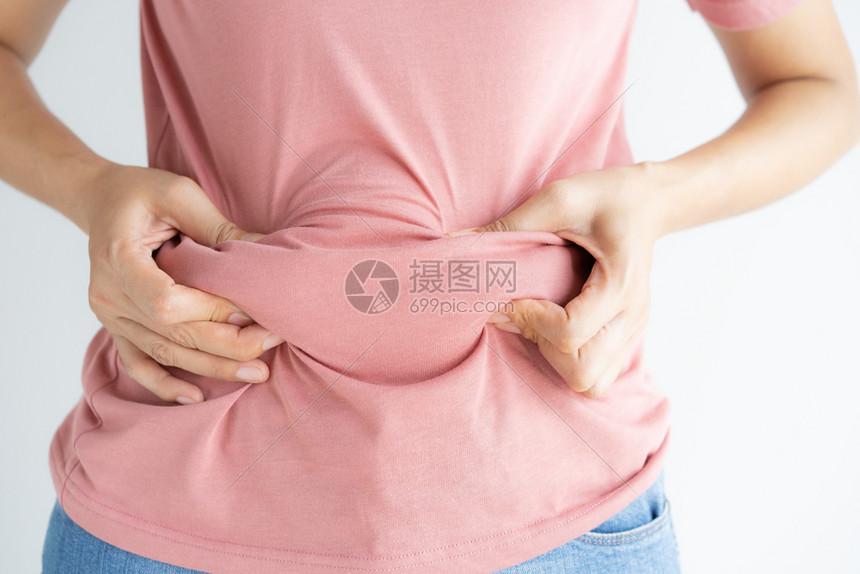 重量腰部牛仔裤妇女将自己的腹部脂肪和纤维素粘在白色背景上的妇女体重减瘦前的妇女形成健康的胃肌肉概念以及图片