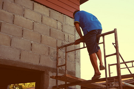 腰带堵塞工人正在爬上脚手架建造房子平台图片