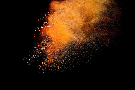 泰国橙色粉末在黑背景下爆炸的冷冻运动结发光的图片