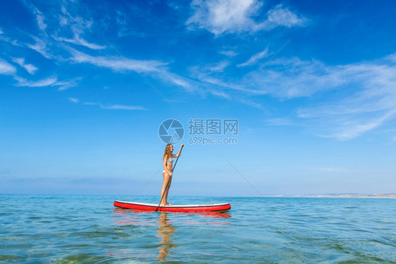 自然站立海一个美丽的女人在阳光明媚的日子里练习划桨图片