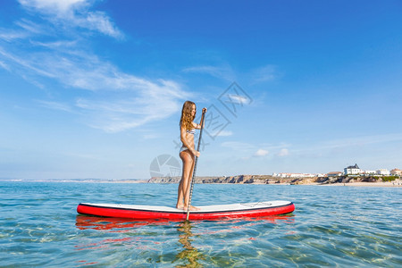 一个美丽的女人在阳光明媚的日子里练习划桨木板海登机图片