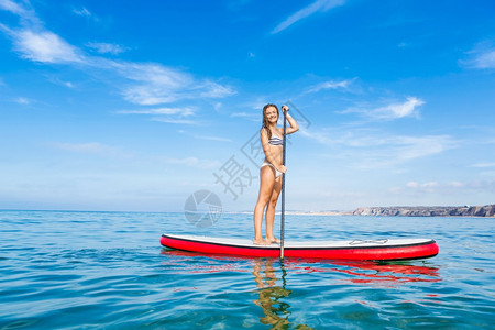 夏天一个美丽的女人在阳光明媚的日子里练习划桨板冲浪锻炼图片