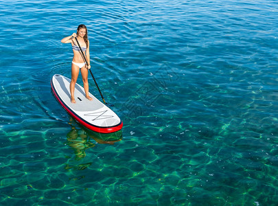 海一个美丽的女人在阳光明媚的日子里练习划桨户外女孩图片