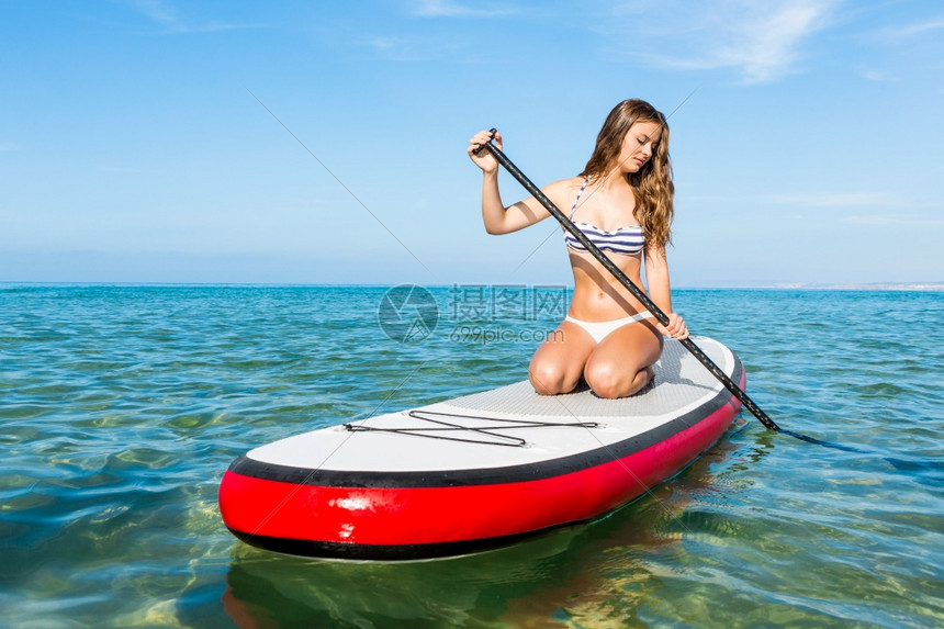 夏天一个美丽的女人在阳光明媚的日子里练习划桨假期木板图片