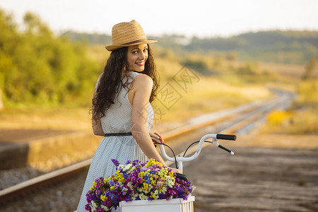 一个美丽的年轻女子骑着自行车满是野花骑术女士旅行图片