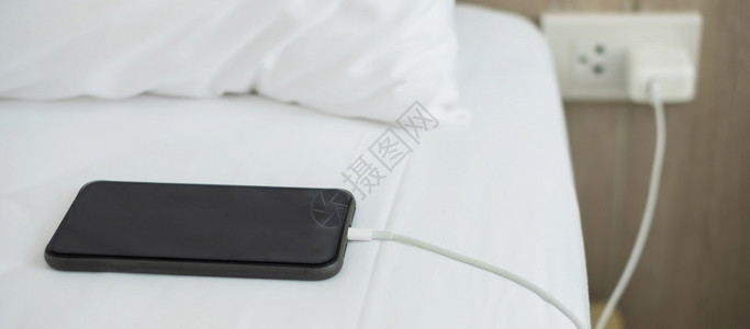 在线的家里卧室床上用手机智能充电池技术多种分享和生活方式概念在家庭卧室的床上使用多式共享和生活方概念插头收费图片