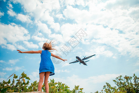 海滩快乐的小女孩在天空中享受飞机的风景快乐穿着服装女孩享受天空景色孩子想像力图片