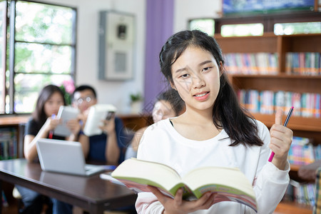 在图书馆抱着书本学习的亚洲女孩图片