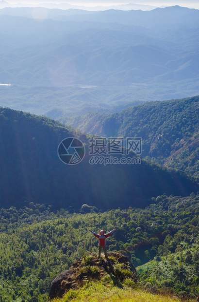 登山者站在顶享受日出高度放松背包图片