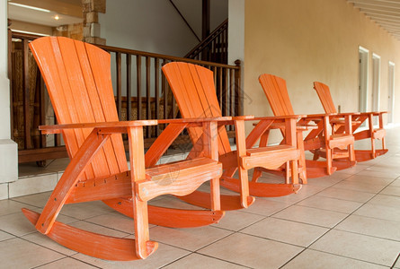 粉色的放松在一个热带度假胜地的门廊上通常布置的橙色木制摇椅目的图片