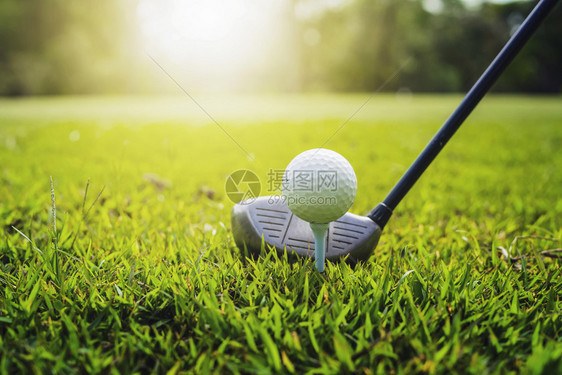 球座推杆玩绿色草地日落时高尔夫球俱乐部和高尔夫球图片