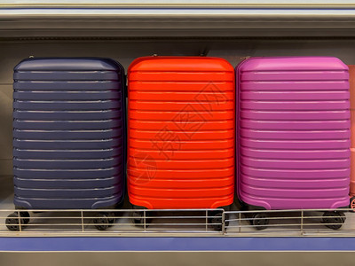 塑料运输包储存架上展示的3种不同颜色现代轮式手提箱图片