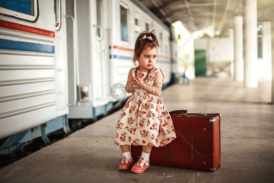 快乐的在小火车站穿着旧衣服和行李箱的可爱白种女孩小火车站童年图片