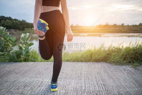 运动员健康年轻女子在公园培训前户外运动中暖身复制女士图片