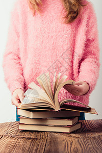 页面读几本关于一名身穿粉红色毛衣和蓝牛仔裤垂直照片的木桌少女书该孩穿着粉色毛衣和蓝牛仔裤学习背景图片