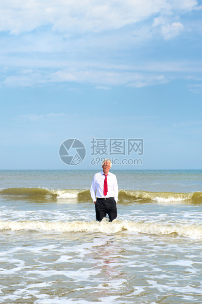 放松身穿正式西装的生意人站在海上赤脚北图片