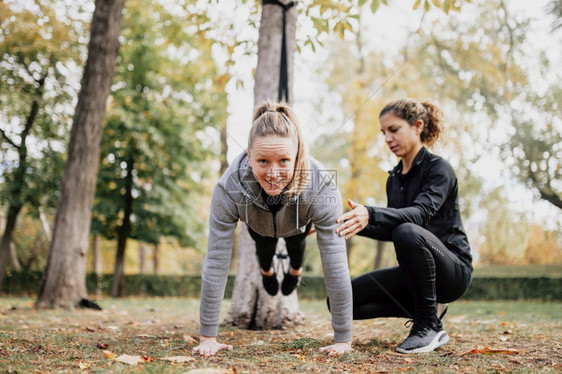 重量力运动妇女在公园外接受与Trax一起培训的妇女图片