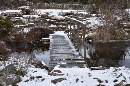 季节木制的冬环足桥穿过一条小溪下雪的图片